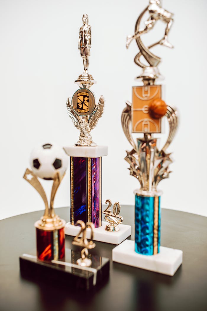 An assortment of sports trophies featuring different designs and sports, displayed on a table.